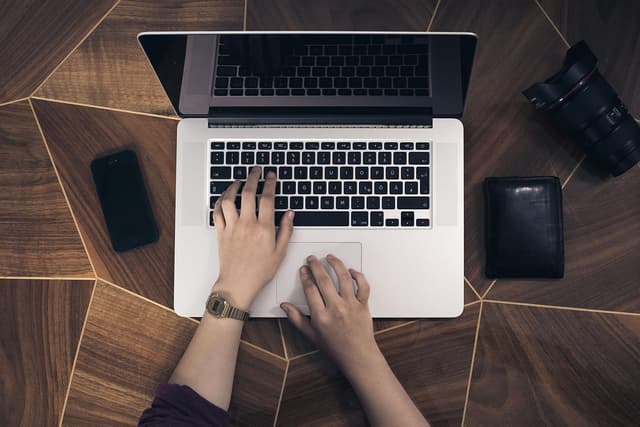 Person typing on a laptop at a desk, illustrating a donor completing an agentic payment through an AI chat