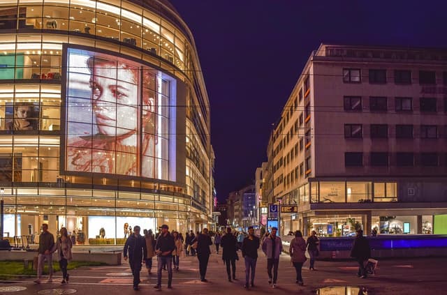 Evening shoppers outside lit storefronts on a European retail street, the consumer backdrop to the Klarna shareholder investigation